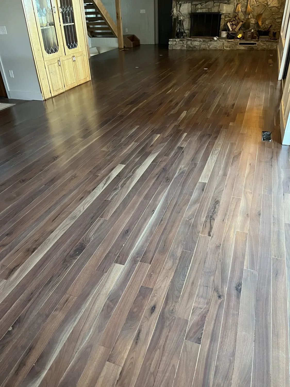 Refinished hardwood flooring in a living room with stone fireplace