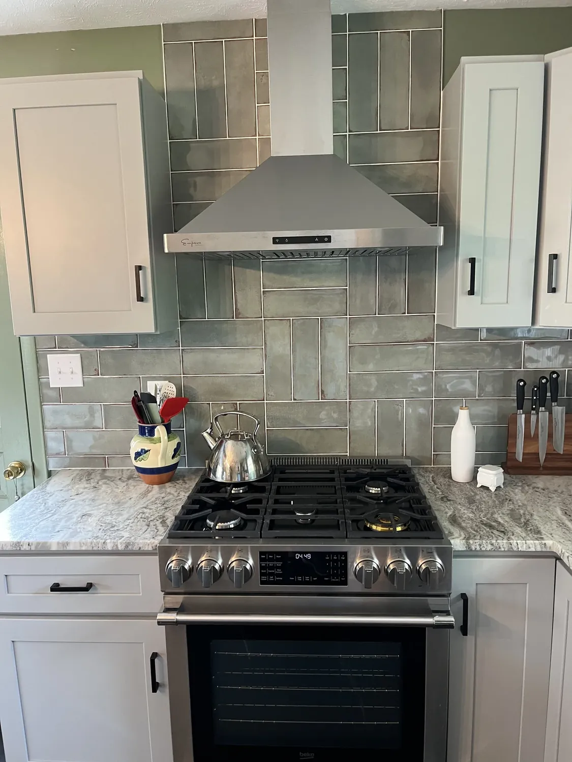 Gas range with stainless hood and gray tile surround