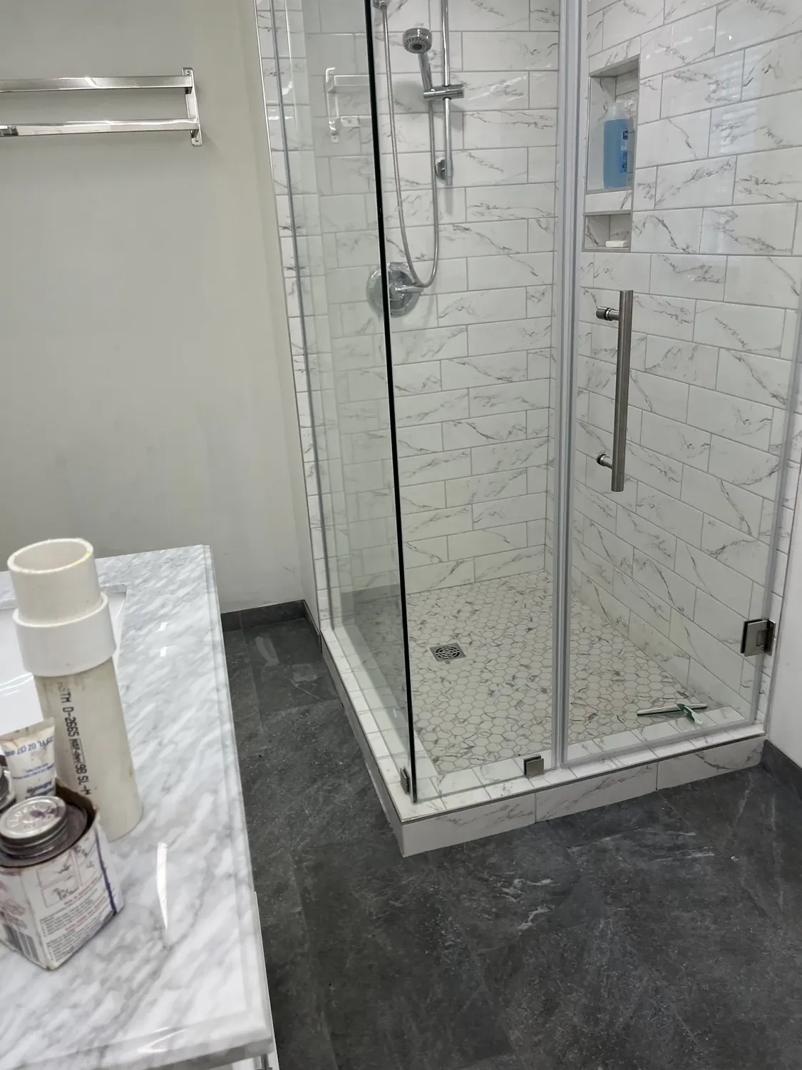 Walk-in shower with marble-look tile and frameless glass door